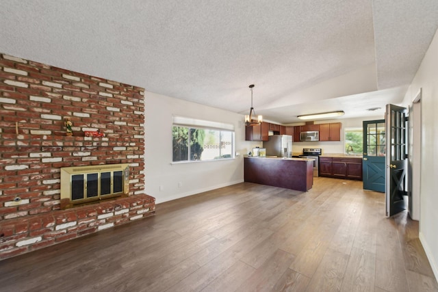 unfurnished living room featuring a sink, lofted ceiling, a fireplace, and wood finished floors