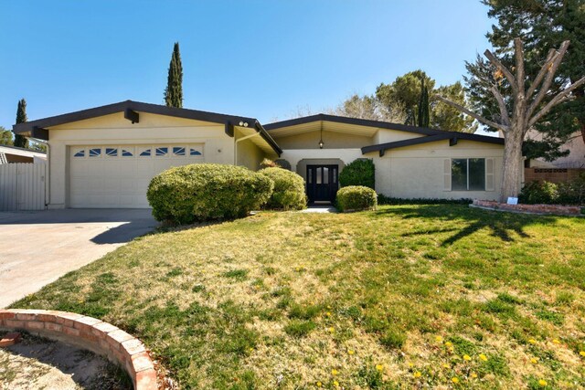view of front of home featuring fence, an attached garage, concrete driveway, a front yard, and stucco siding
