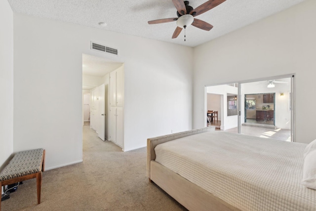 bedroom featuring light colored carpet, visible vents, ceiling fan, and a textured ceiling