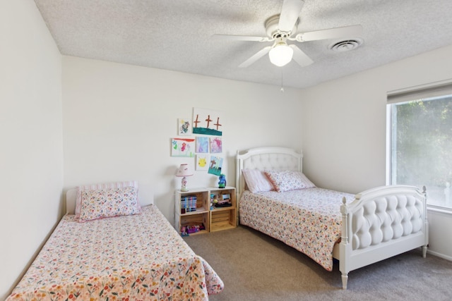 carpeted bedroom featuring a textured ceiling, visible vents, and ceiling fan