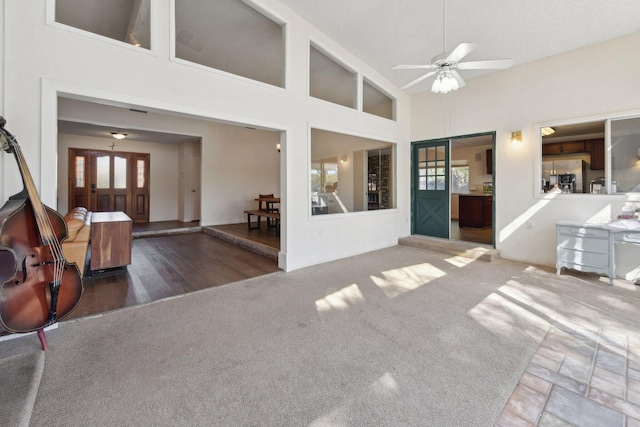 living area featuring a wealth of natural light, high vaulted ceiling, ceiling fan, and carpet