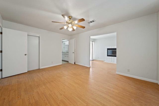 interior space featuring light wood-type flooring, a fireplace, visible vents, and baseboards