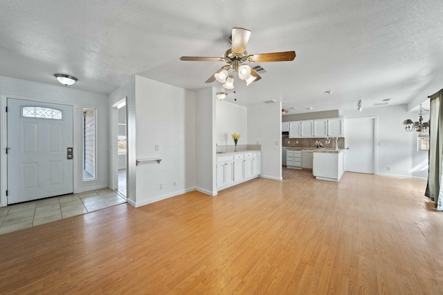 entrance foyer with light wood-style floors, ceiling fan, and a textured ceiling