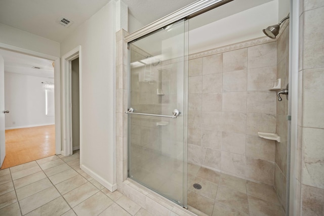 bathroom featuring a stall shower, visible vents, baseboards, and tile patterned floors