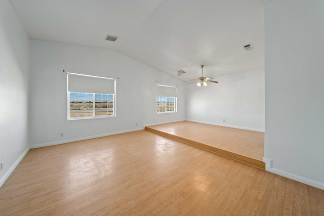 unfurnished room with visible vents, vaulted ceiling, light wood-style flooring, and a ceiling fan