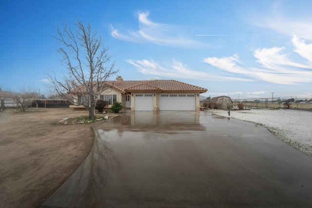 view of front of home featuring fence, a tiled roof, stucco siding, a garage, and driveway