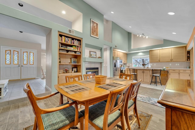 dining space featuring visible vents, high vaulted ceiling, light wood-style flooring, recessed lighting, and a fireplace