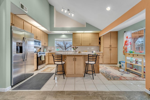 kitchen featuring tile countertops, a breakfast bar area, a kitchen island, light tile patterned flooring, and stainless steel appliances