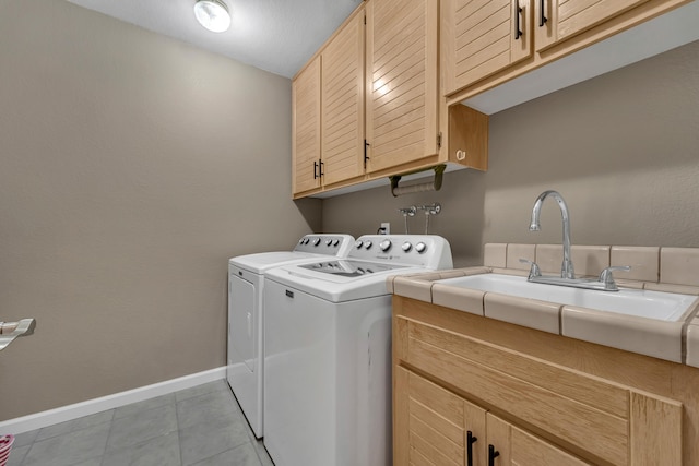 laundry area with washing machine and clothes dryer, baseboards, light tile patterned floors, cabinet space, and a sink