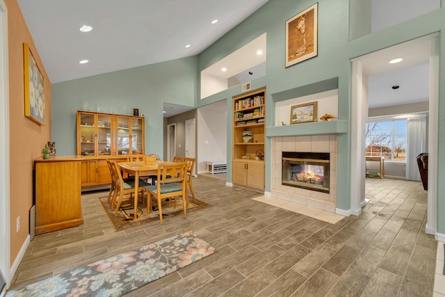 dining area with a tiled fireplace, baseboards, and wood finish floors