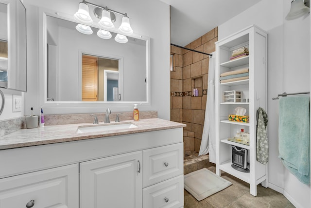 bathroom featuring tiled shower, vanity, and baseboards