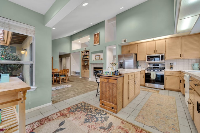 kitchen featuring visible vents, a kitchen island, a fireplace, light tile patterned flooring, and stainless steel appliances