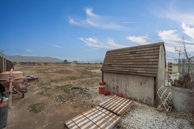 view of yard with a storage shed, fence, a mountain view, and an outdoor structure