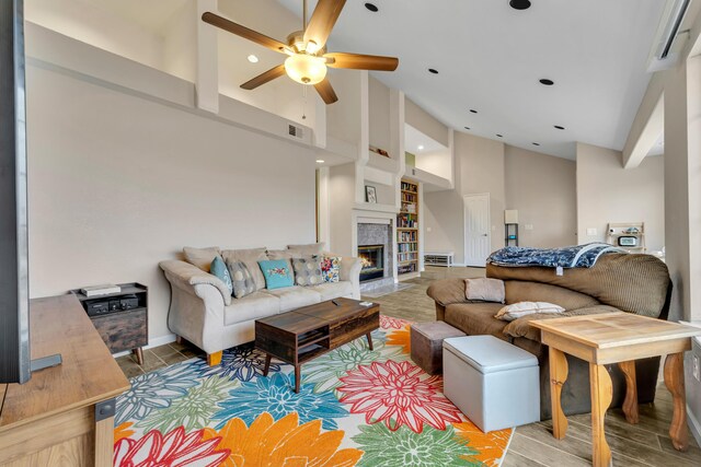 living area with wood finished floors, a ceiling fan, visible vents, high vaulted ceiling, and a tiled fireplace