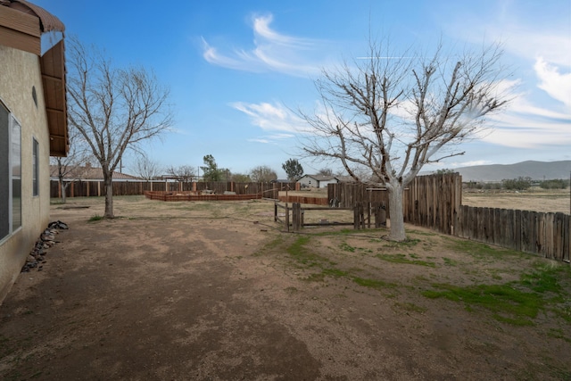 view of yard featuring a deck with mountain view and fence