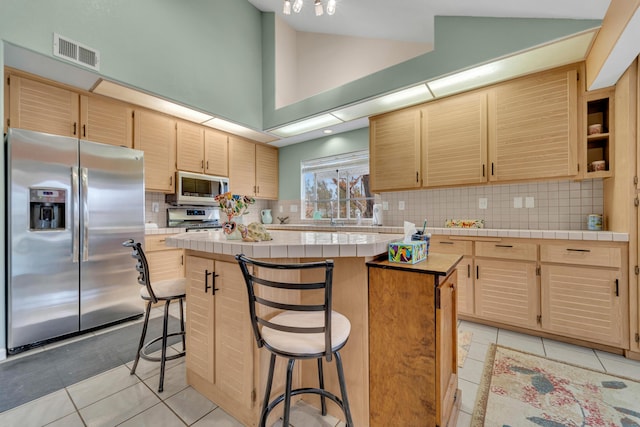 kitchen with light tile patterned flooring, a kitchen island, visible vents, and stainless steel appliances