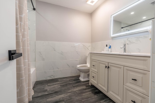 full bathroom with vanity, hardwood / wood-style flooring, toilet, shower / bath combo with shower curtain, and tile walls