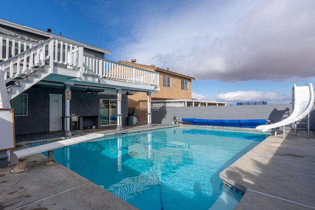 view of swimming pool with a patio area, a diving board, a water slide, and ceiling fan