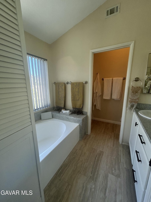38836 Calistoga St, Palmdale, CA 93551 - bathroom featuring vanity, a garden tub, wood finished floors, and lofted ceiling