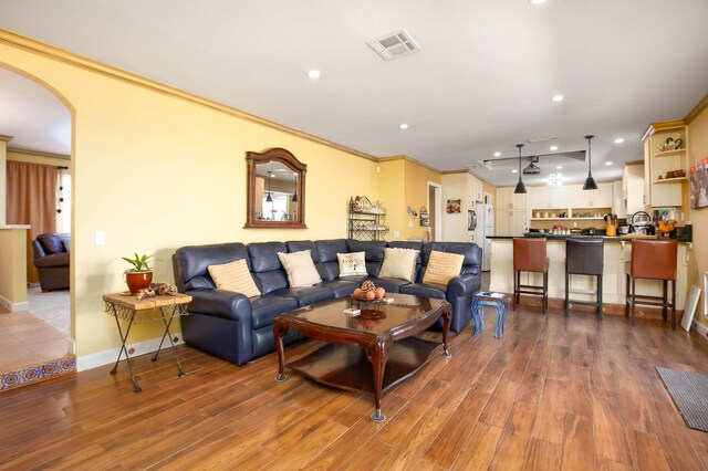 3215 Larwood Dr, Lancaster, CA 93536 - living area featuring visible vents, arched walkways, crown molding, and wood finished floors