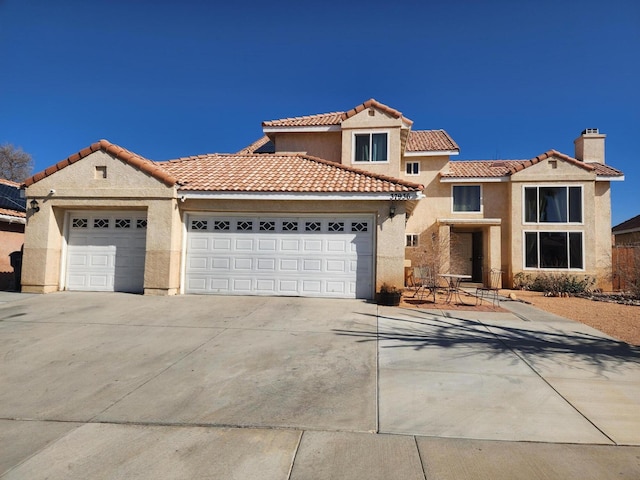 mediterranean / spanish-style house with driveway, a chimney, a tiled roof, an attached garage, and stucco siding