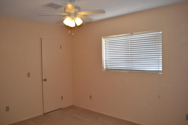 unfurnished room featuring carpet floors, ceiling fan, and visible vents