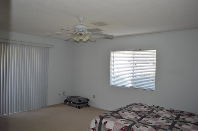 unfurnished bedroom with light carpet, a ceiling fan, visible vents, and a textured ceiling