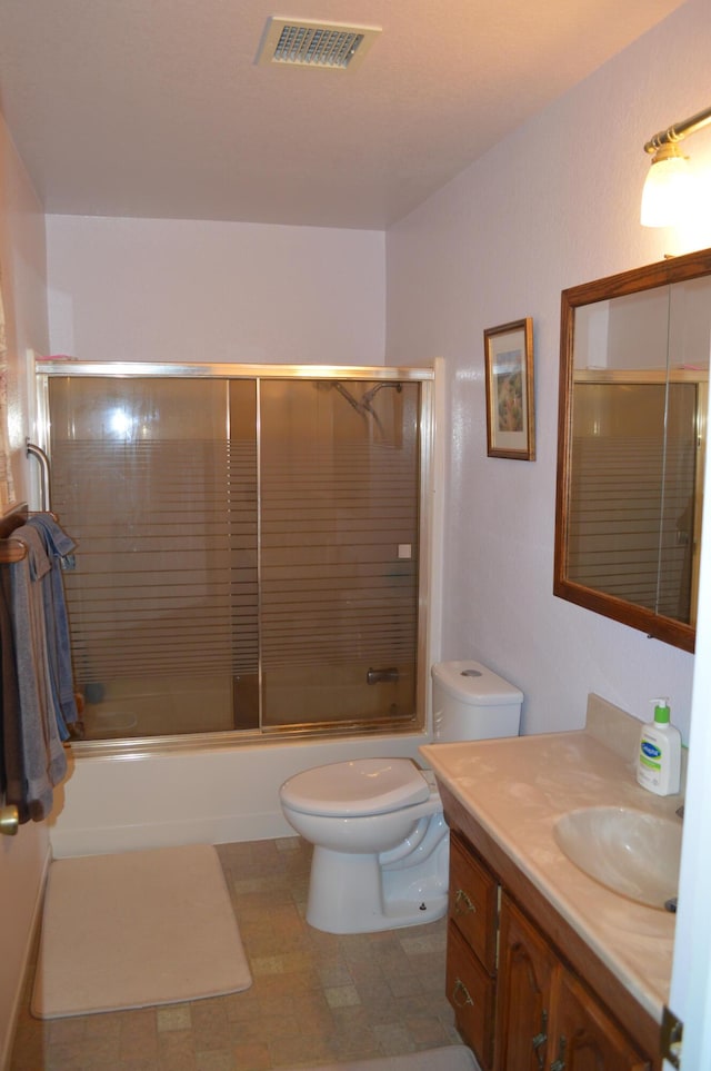 bathroom featuring visible vents, shower / bath combination with glass door, vanity, and toilet