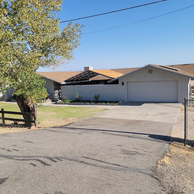 view of front of house with fence, driveway, an attached garage, and stucco siding