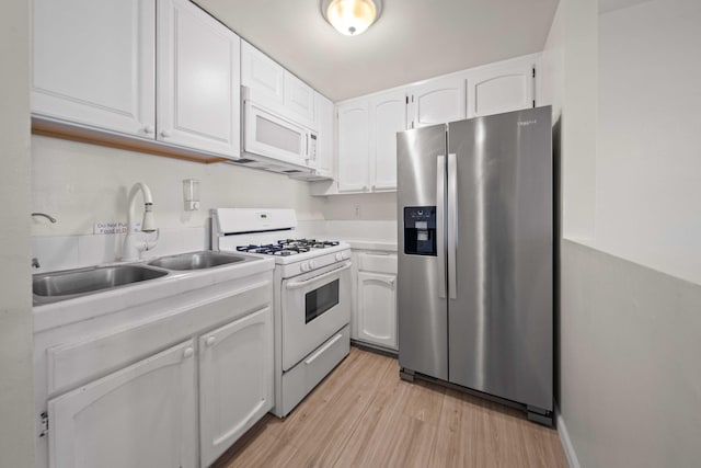 kitchen with white cabinetry, sink, light hardwood / wood-style floors, and white appliances