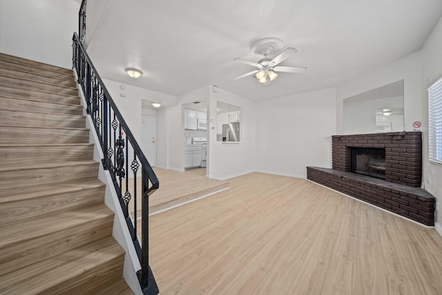 unfurnished living room with ceiling fan, light hardwood / wood-style flooring, and a brick fireplace