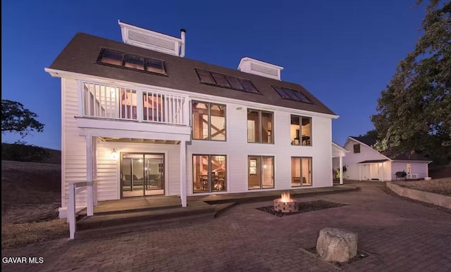 30508 Buckskin Dr, Tehachapi, CA 93561 - back of house at night featuring a balcony, a fire pit, and a patio area
