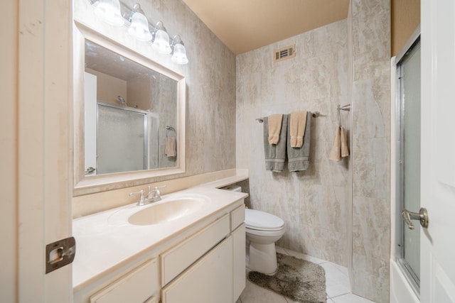 full bathroom featuring enclosed tub / shower combo, tile patterned floors, toilet, vanity, and tile walls