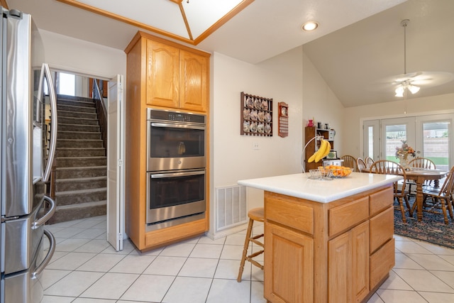 kitchen featuring a center island, a breakfast bar area, ceiling fan, light tile patterned floors, and stainless steel appliances