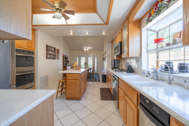 kitchen featuring ceiling fan, sink, stainless steel appliances, a breakfast bar area, and a kitchen island