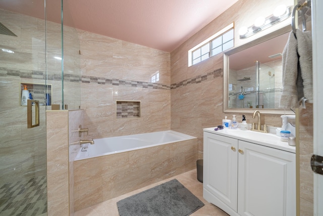 bathroom featuring plus walk in shower, vanity, tile patterned floors, and tile walls