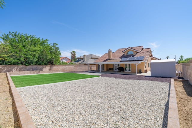 rear view of house featuring a lawn, a patio, and solar panels