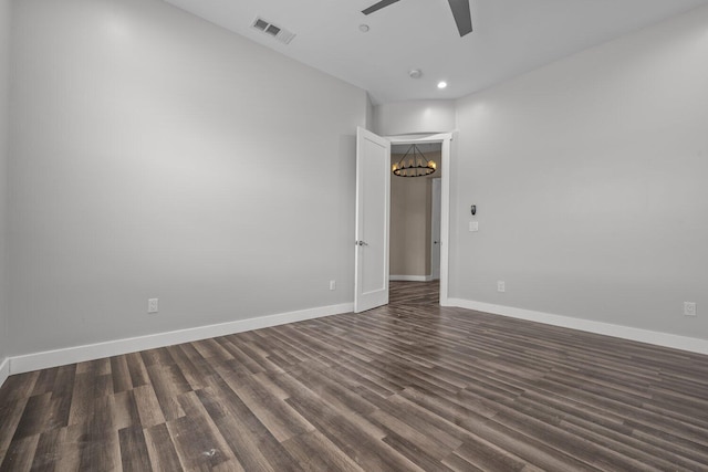 spare room with ceiling fan with notable chandelier and dark hardwood / wood-style flooring