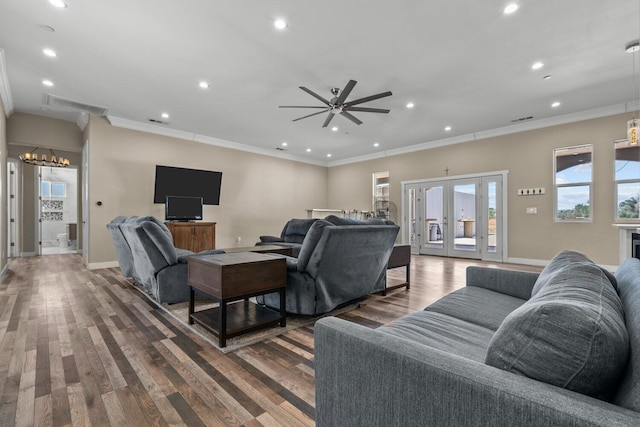 living room featuring hardwood / wood-style floors, ceiling fan with notable chandelier, ornamental molding, and french doors