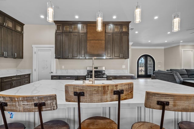 kitchen with dark brown cabinets, an island with sink, decorative light fixtures, and french doors