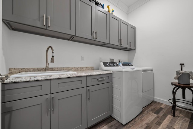 laundry area featuring sink, cabinets, separate washer and dryer, dark hardwood / wood-style flooring, and ornamental molding