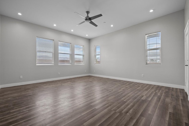 empty room featuring ceiling fan, plenty of natural light, and dark hardwood / wood-style floors