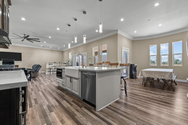 kitchen featuring a kitchen breakfast bar, a kitchen island with sink, ceiling fan, pendant lighting, and dishwasher