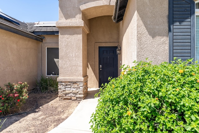 doorway to property featuring stucco siding and stone siding