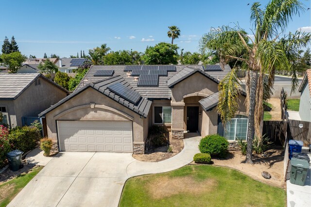 view of front of property featuring driveway, stucco siding, fence, an attached garage, and roof mounted solar panels