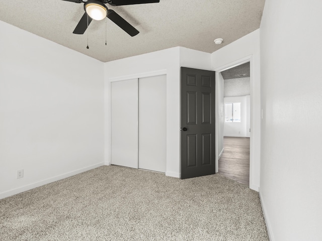 unfurnished bedroom featuring light carpet, a textured ceiling, a closet, and ceiling fan