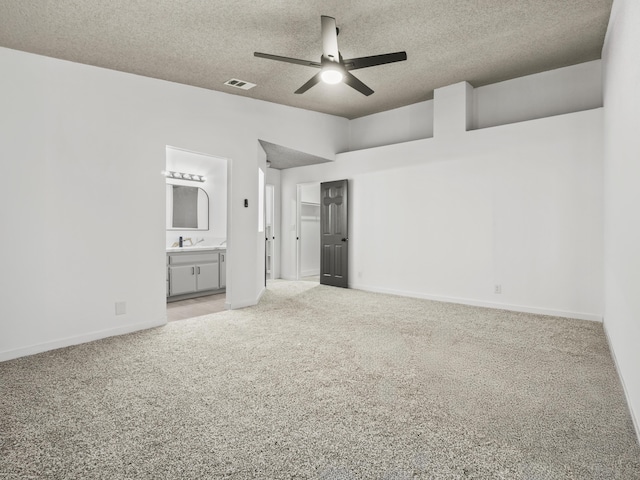 unfurnished bedroom featuring carpet floors, ensuite bathroom, ceiling fan, and a textured ceiling