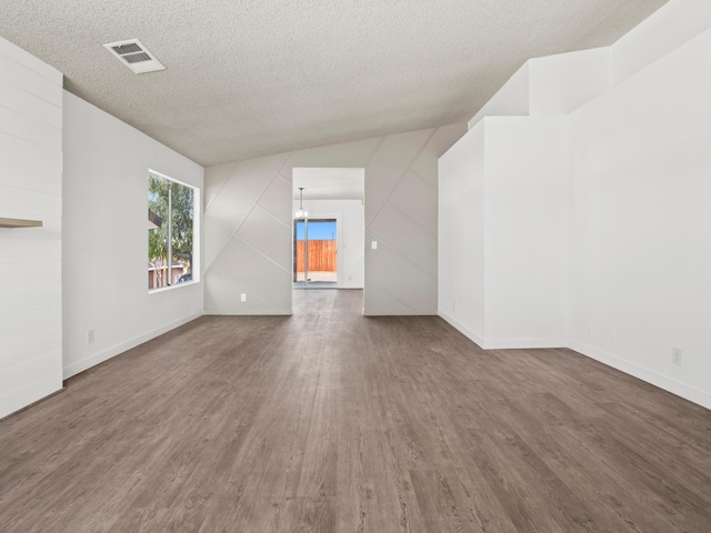 unfurnished living room featuring hardwood / wood-style floors, a textured ceiling, lofted ceiling, and a notable chandelier