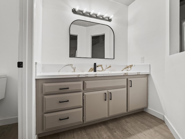 bathroom with wood-type flooring, vanity, and toilet