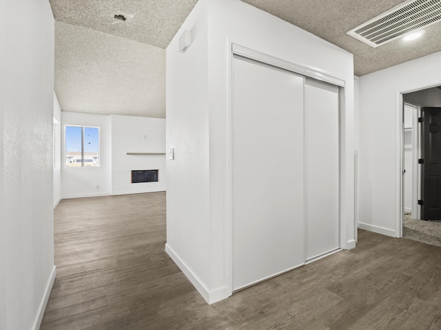 corridor with a textured ceiling and dark wood-type flooring